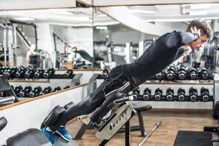 En man som tränar rygglyft på en bänk